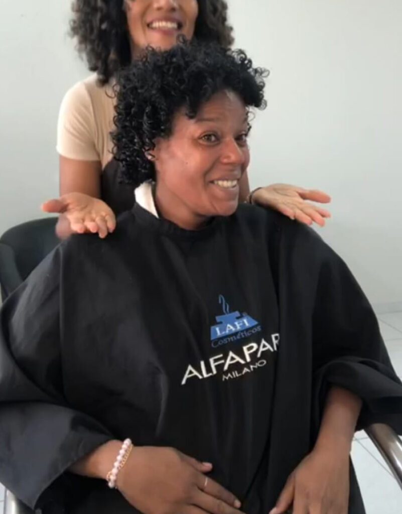 Cliente depois: cabelo cacheado definido, sorrindo.